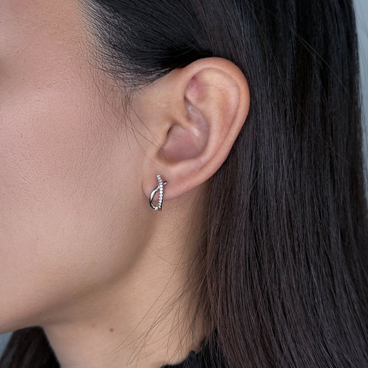Silver crossed stud earrings worn by model on a gray background