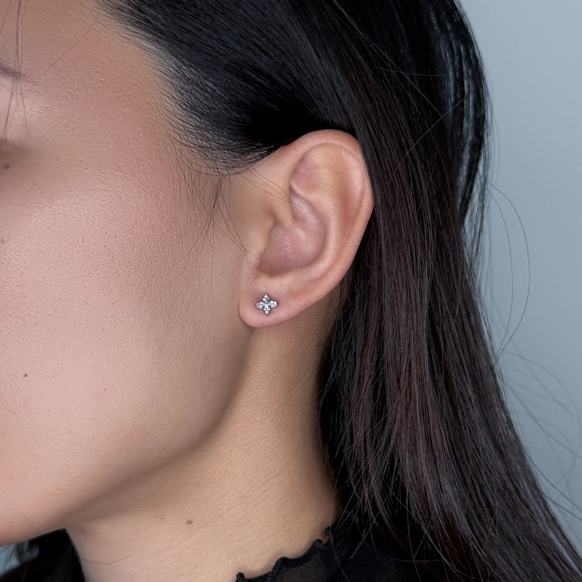 Silver clover star studs worn by model on a gray background