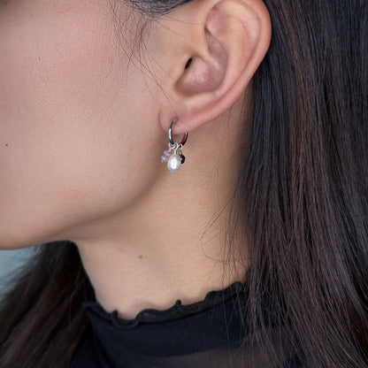 Silver huggies hoop earrings with pearl and glass charms worn by model on a gray background