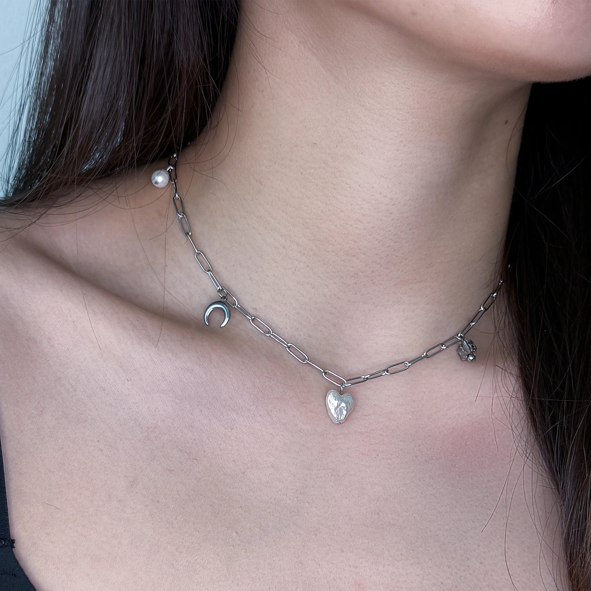 Silver charm necklace with heart pearl, glass beads, and steel charms worn on a model
