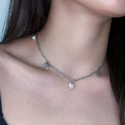 Silver charm necklace with heart pearl, glass beads, and steel charms worn on a model