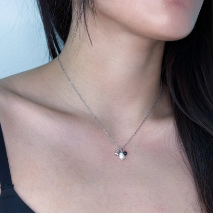 Dainty silver necklace with pearl and glass charms worn on a model