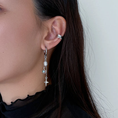 Close-up of a person wearing silver earrings with beads and star charms.