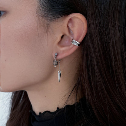 Close-up of a person wearing earrings with a neutral background