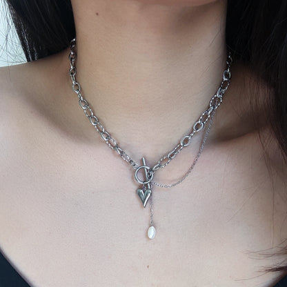 Silver paperclip chain necklace with a unique pendant worn by a person