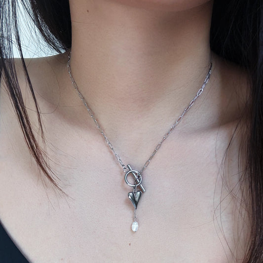 Silver necklace with a heart-shaped pendant worn by a person