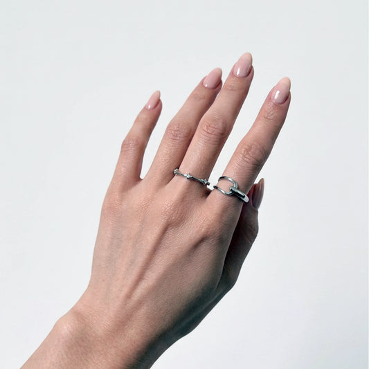 Sterling silver stackable rings with a starling band ring and geometric ring on a gray background